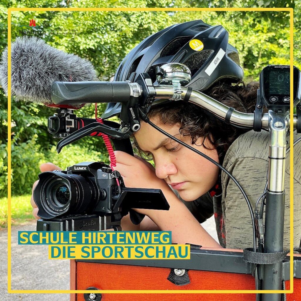 Die Sportschau. Ein Schüler mit Fahrradhelm auf dem Kopf und Kamera in der Hand, sitzt in einem Lastenrad und blickt konzentriert auf den Monitor der Kamera.